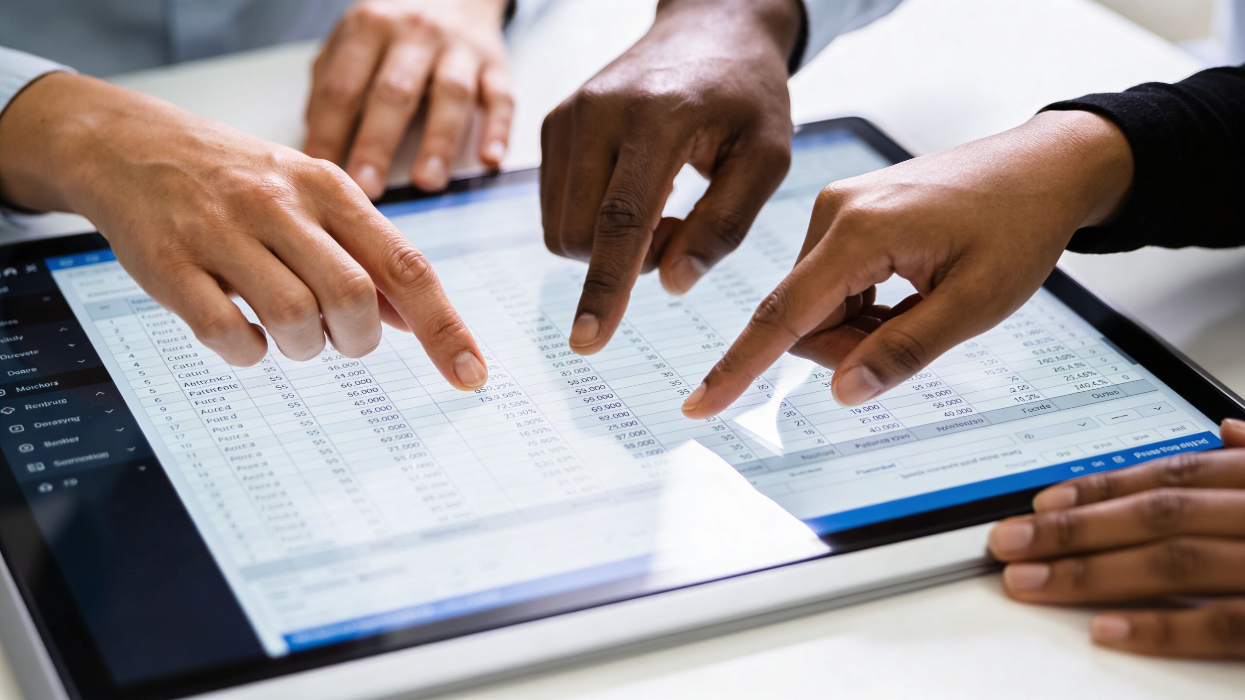 Persone diverse analizzano dati finanziari su un grande schermo interattivo durante una riunione di lavoro collaborativa.